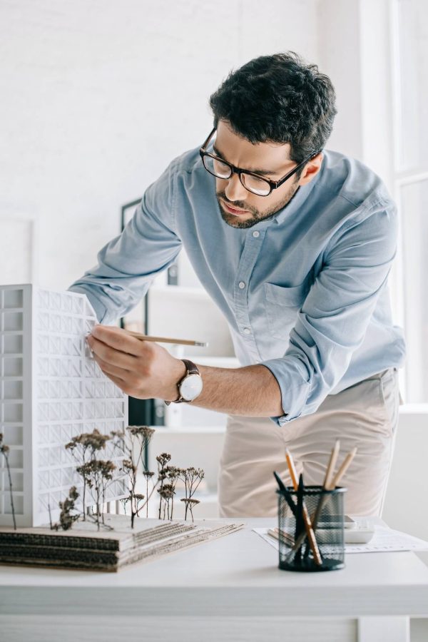 handsome-architect-working-with-architecture-model-on-table-in-office