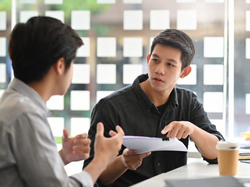 Asian young man consulting with paper document on modern office.