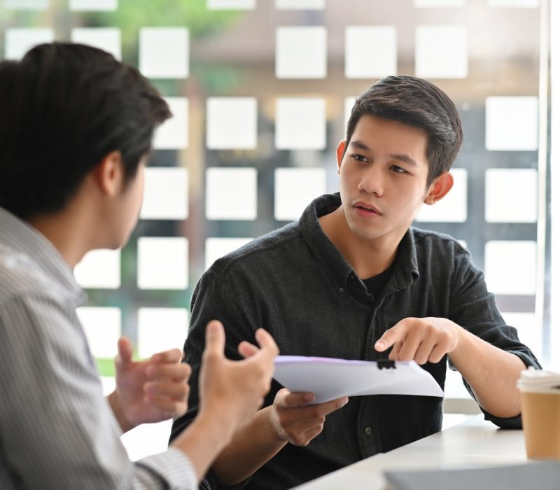 Asian young man consulting with paper document on modern office.