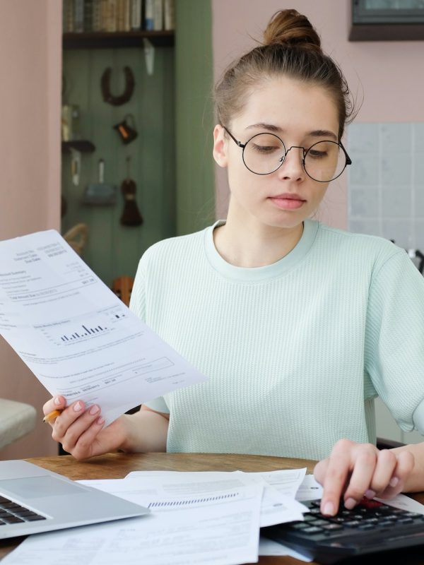 Young beautiful woman budgeting, managing utilities expenses, writing financial plan