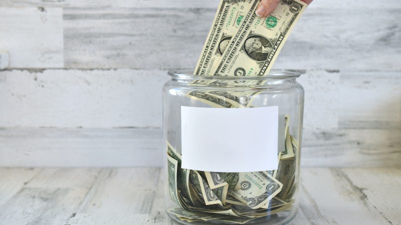 Jar of money cash for donation, fundraiser fundraising collection - hand in frame blank copy space