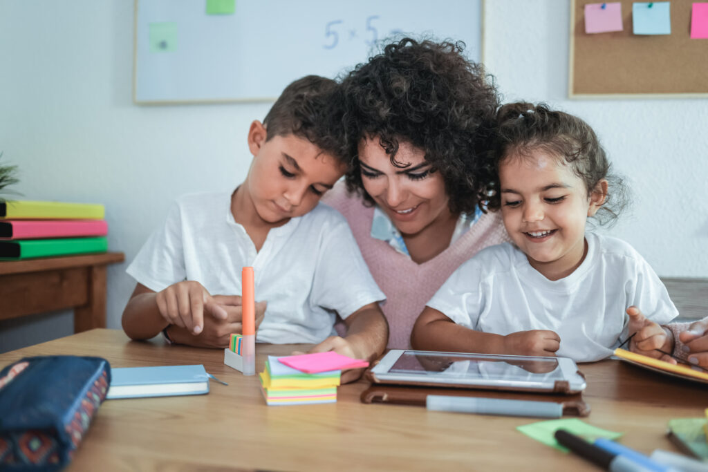 Teacher using tablet with children in kindergarten school - Focus on girl face