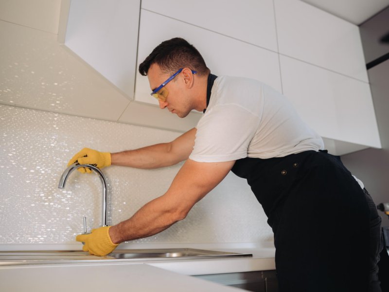 Maintenance man installing plumbing equipment in the kitchen