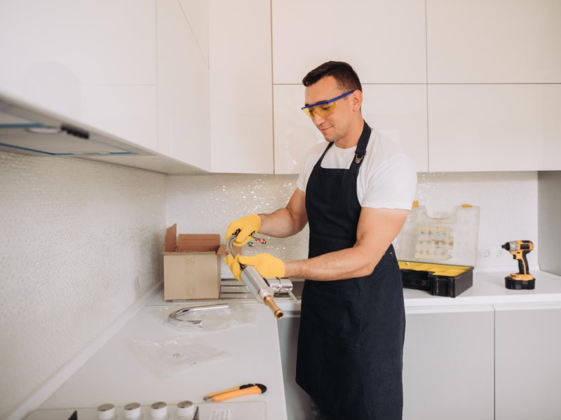 Maintenance man is going to install plumbing equipment in the kitchen