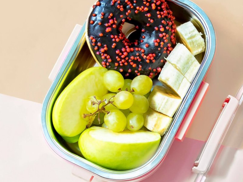 Catering food prepared in storage container with compartment with doughnut,apple,banana,grape