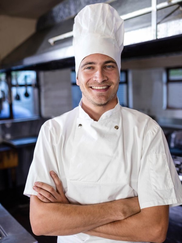 Male chef standing with arms crossed in kitchen