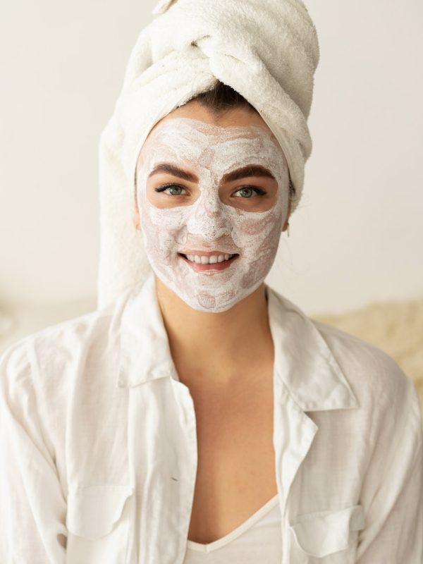 Beautiful woman applying facial mask