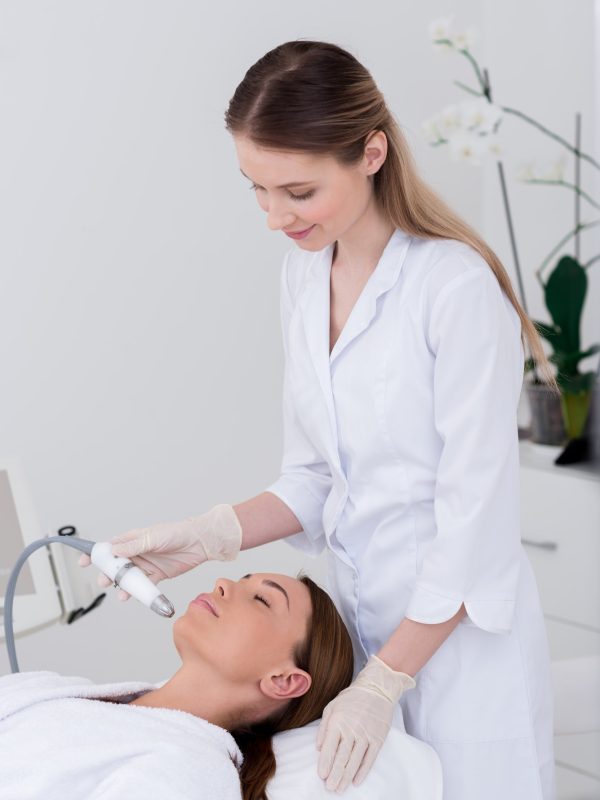 young woman getting facial treatment in cosmetology salon