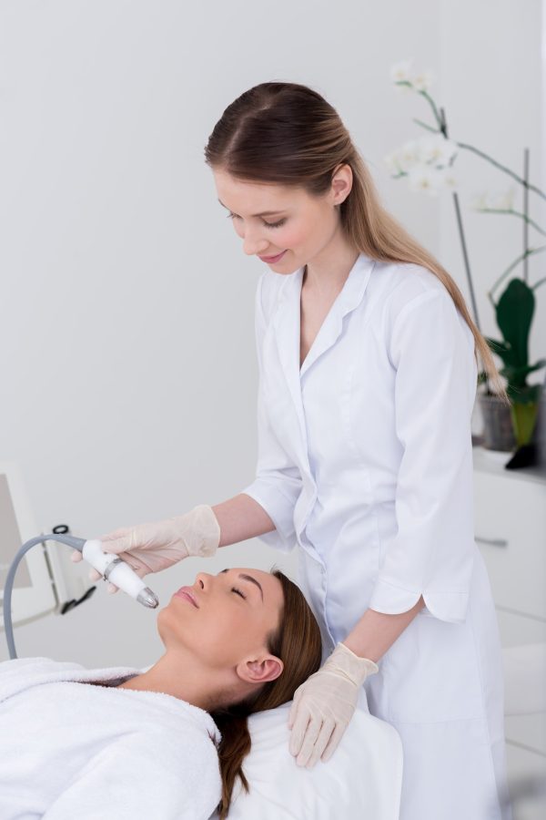 young woman getting facial treatment in cosmetology salon