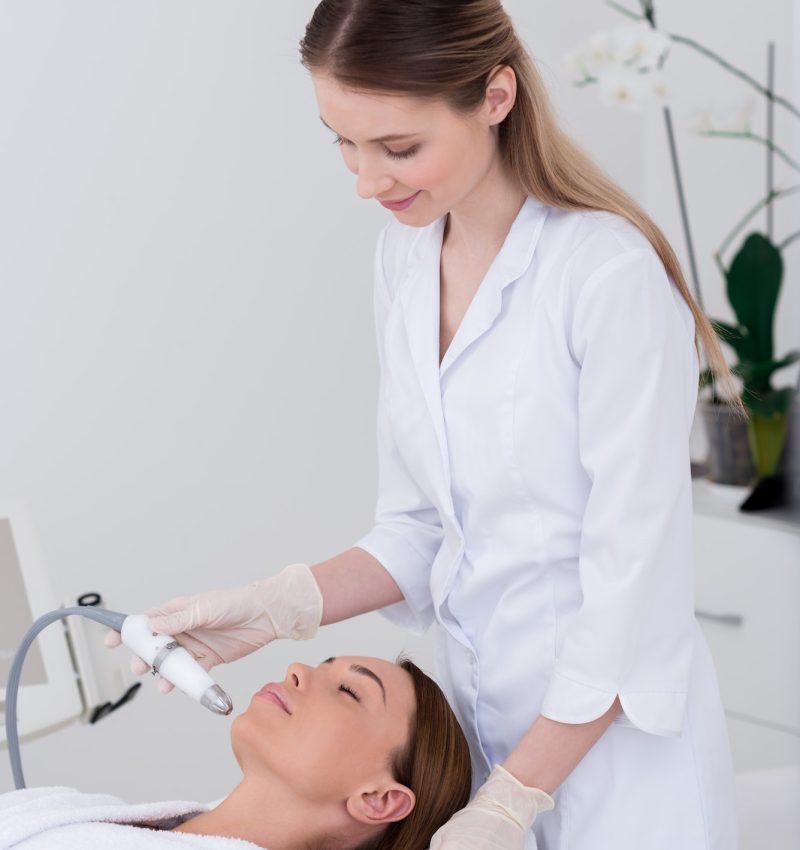 young woman getting facial treatment in cosmetology salon